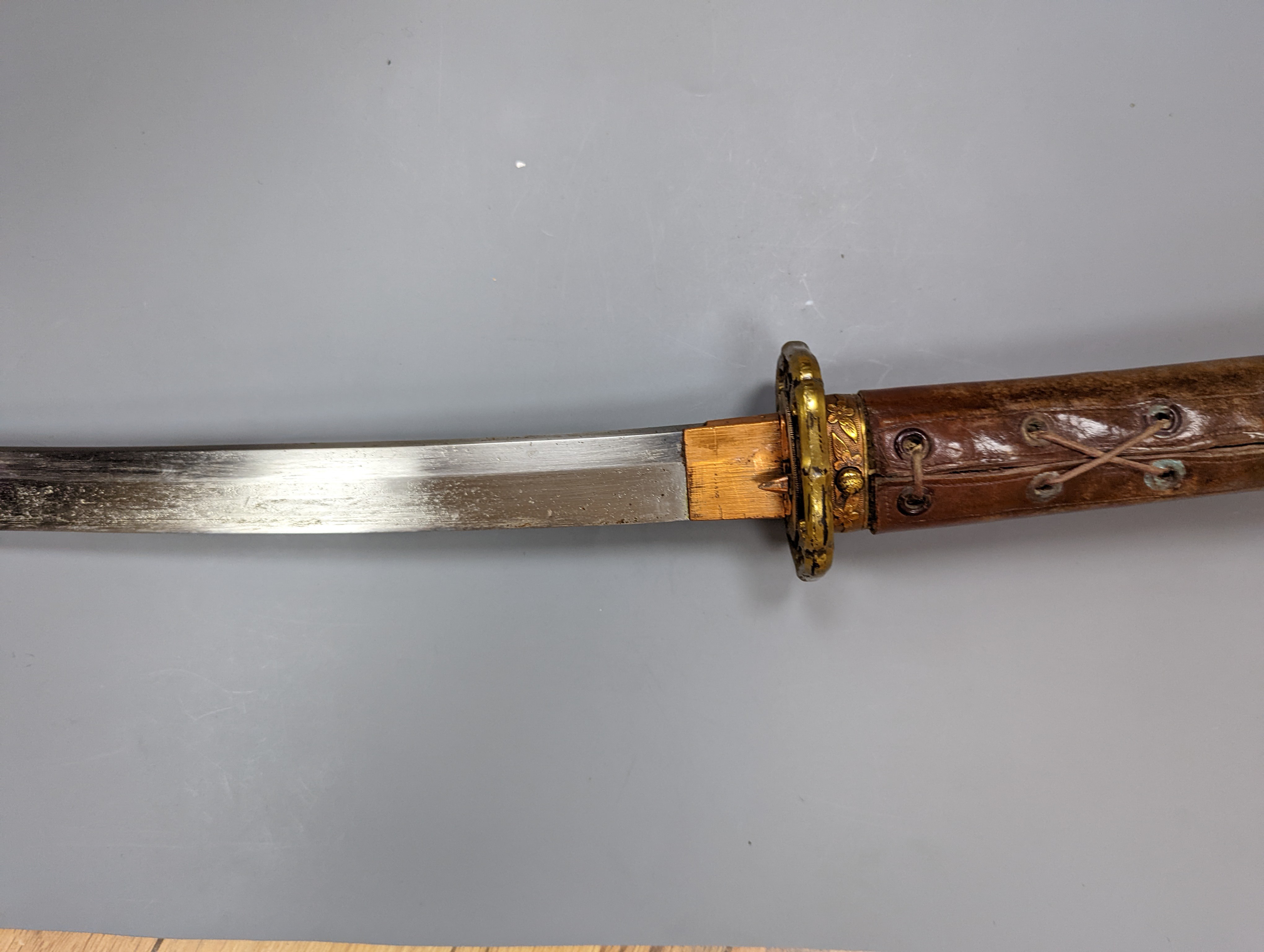 A Japanese Katana with leather covered sheath, plaque reading ‘Presented to Capt. S. Mear Telecoms B.M.A’ 93 cms long.